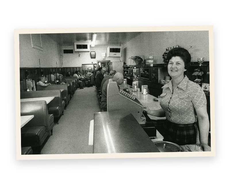 A black and white photo of a woman in a diner