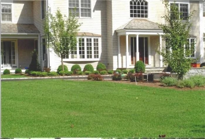Suburban townhouse with white columns, front porch, and manicured green lawn