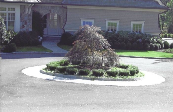 Circular landscaped island in a driveway in front of a house