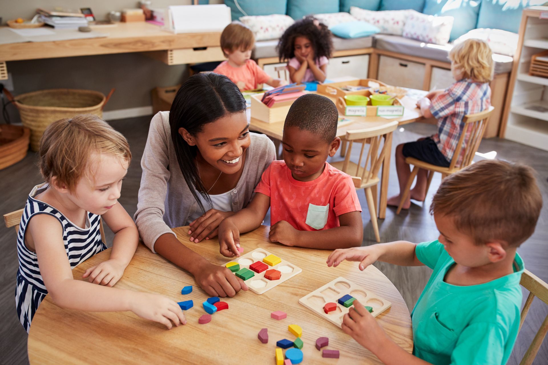 Teacher and pupils using wooden shapes in a preschool setting. Teacher and pupils using wooden shapes in a preschool setting.