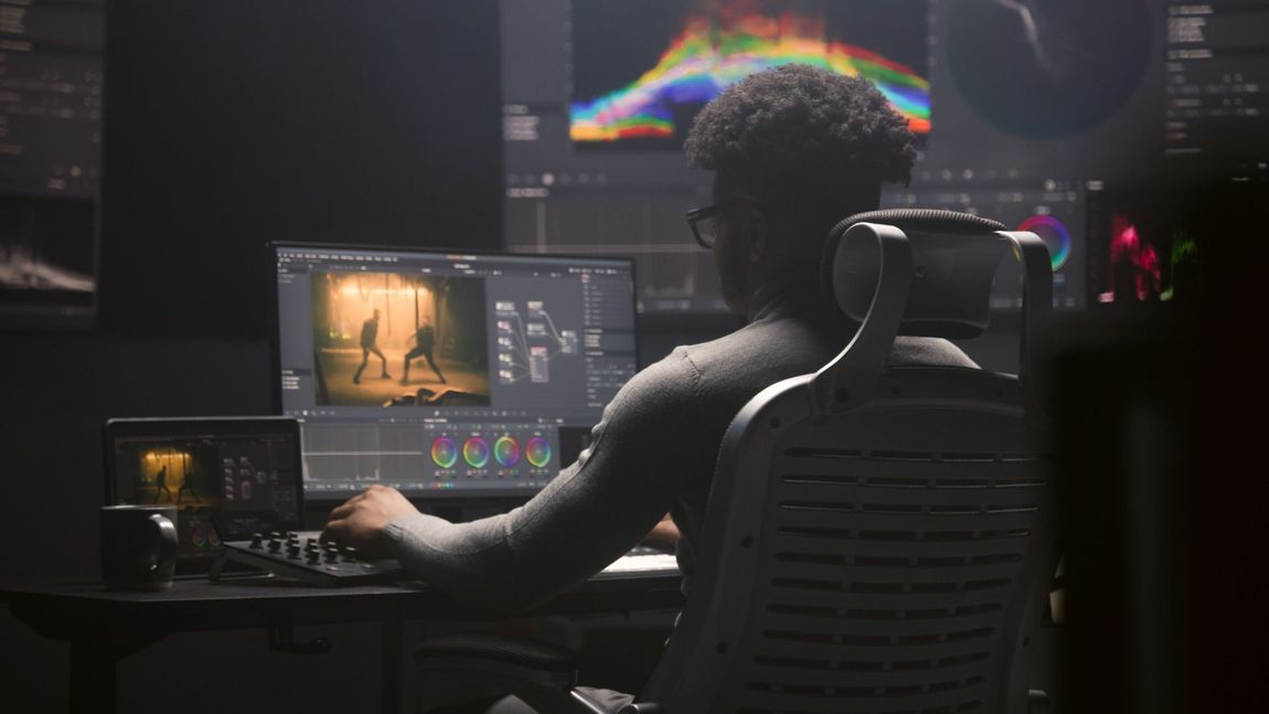 Person color grading video on a computer in a dark room.