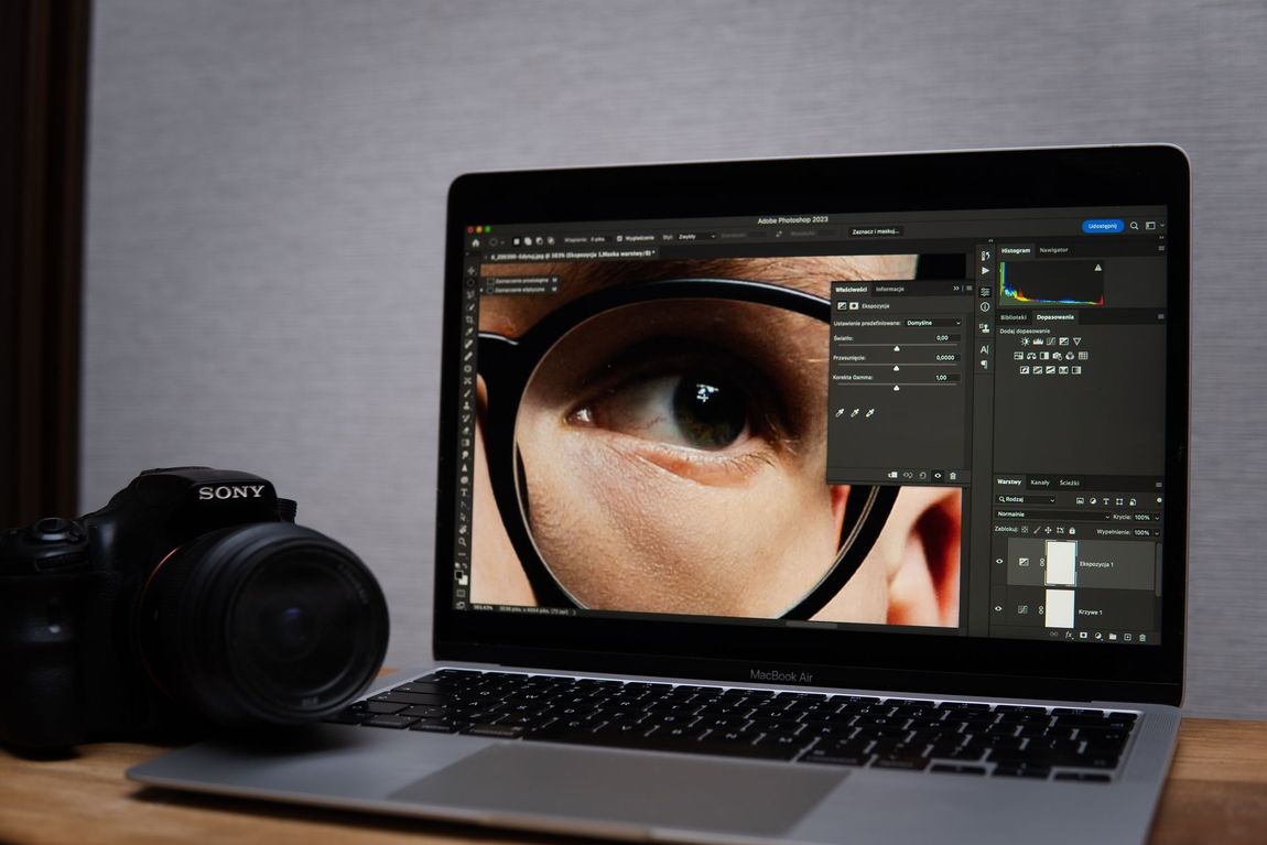 Laptop with photo editing software displaying a close-up of an eye; camera sits beside the computer.