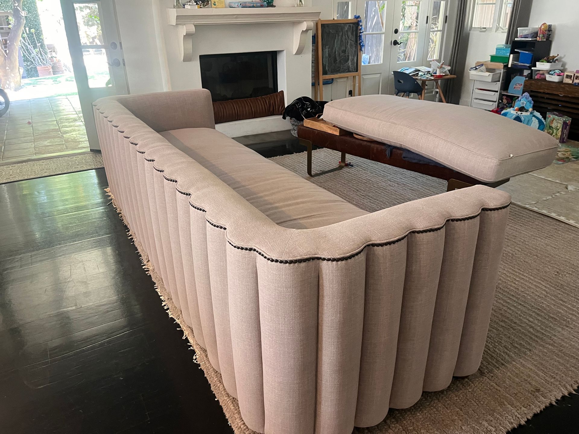 Beige sectional sofa in a bright living room with a fireplace and glass coffee table