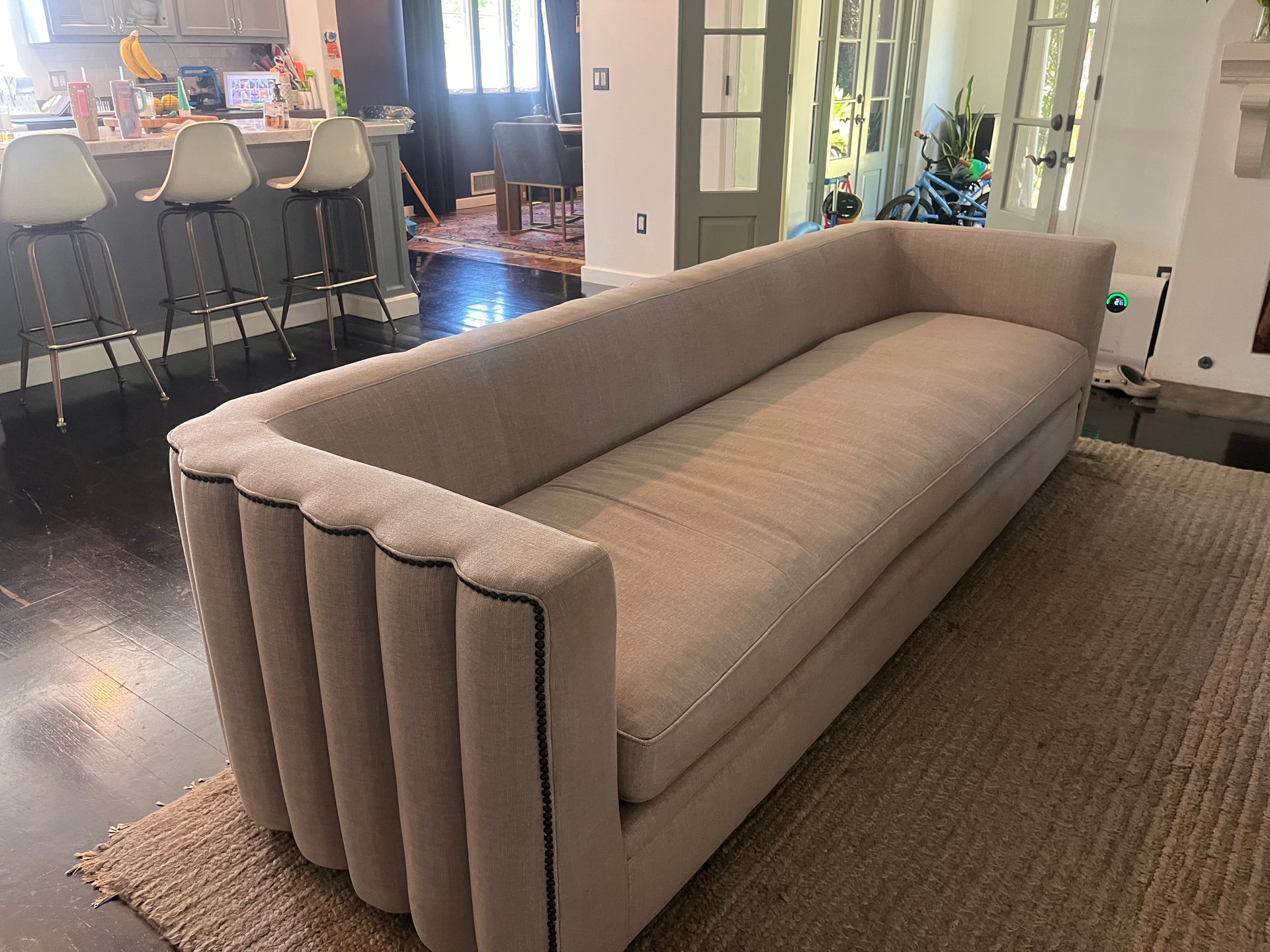 Long beige upholstered sofa in a modern living room with kitchen stools in the background