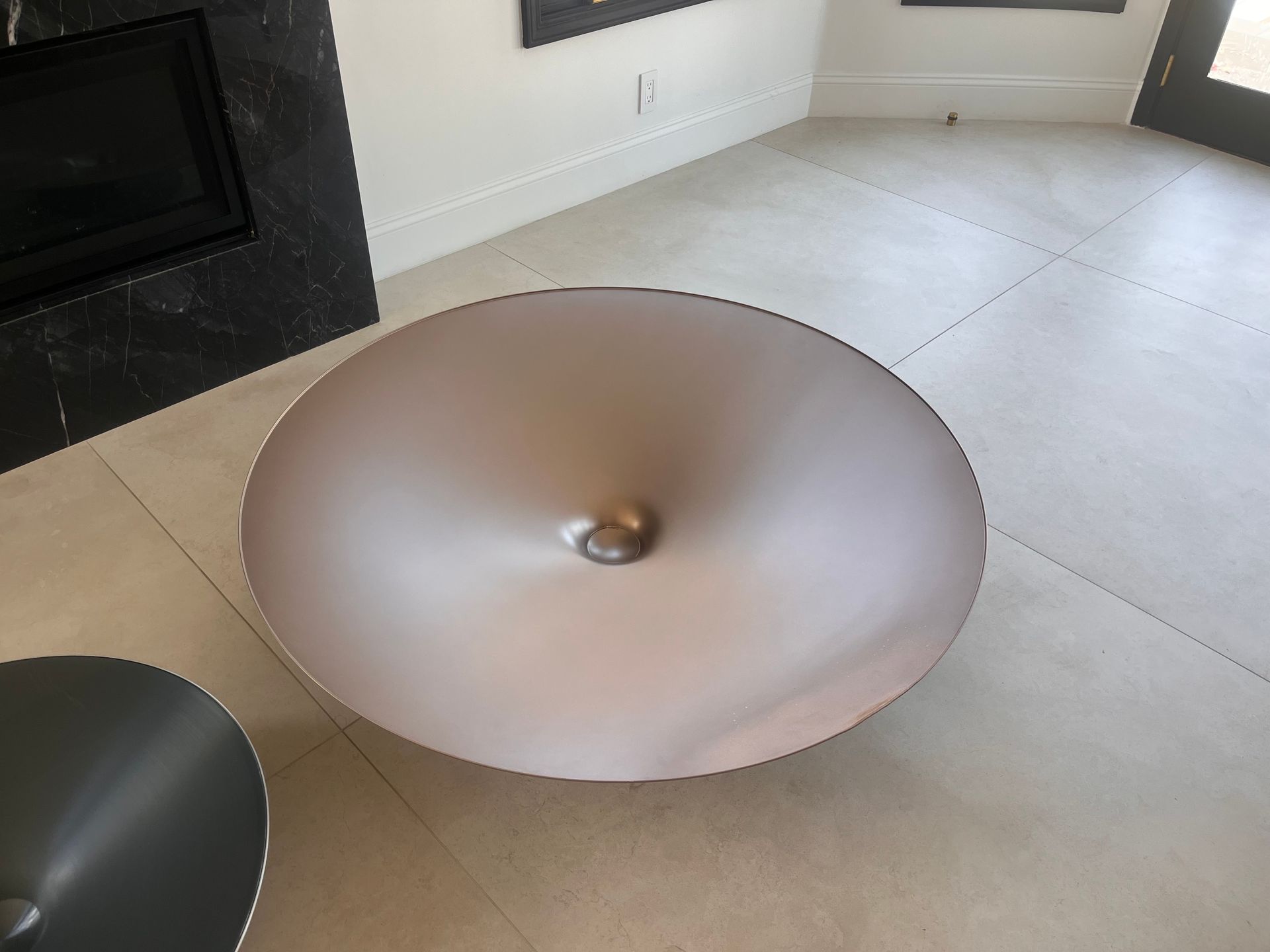 Modern living room with a copper pendant light lying on the floor near a fireplace.