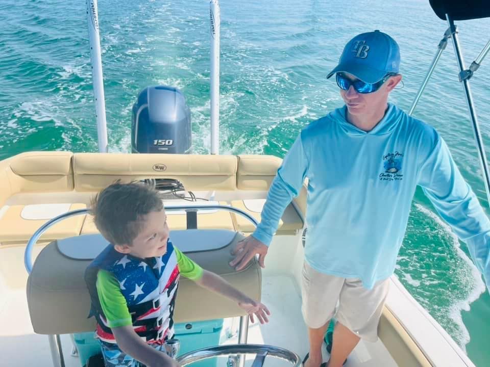 A man and a boy are standing on a boat in the water.