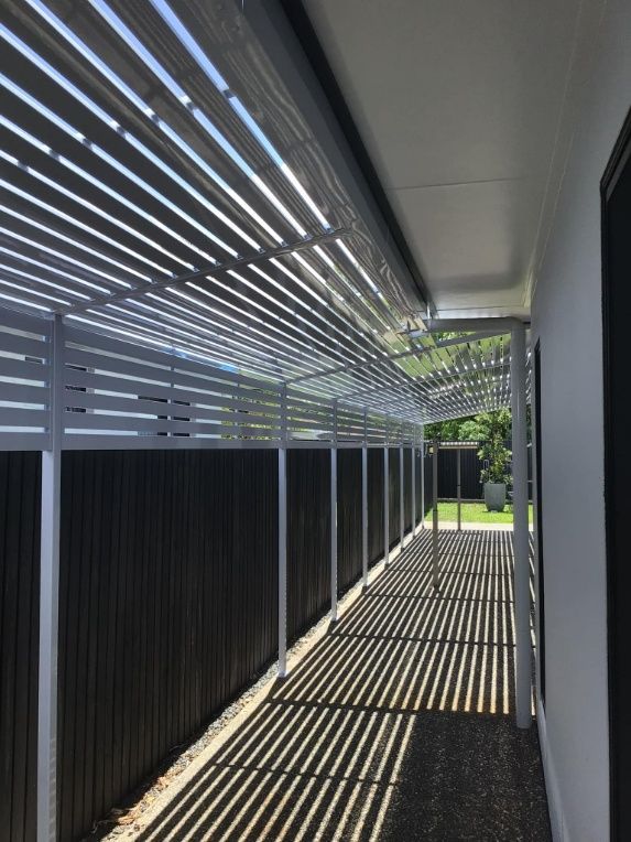 A Covered Walkway With A Black Fence Behind It — Ward's Aluminium in Garbutt, QLD