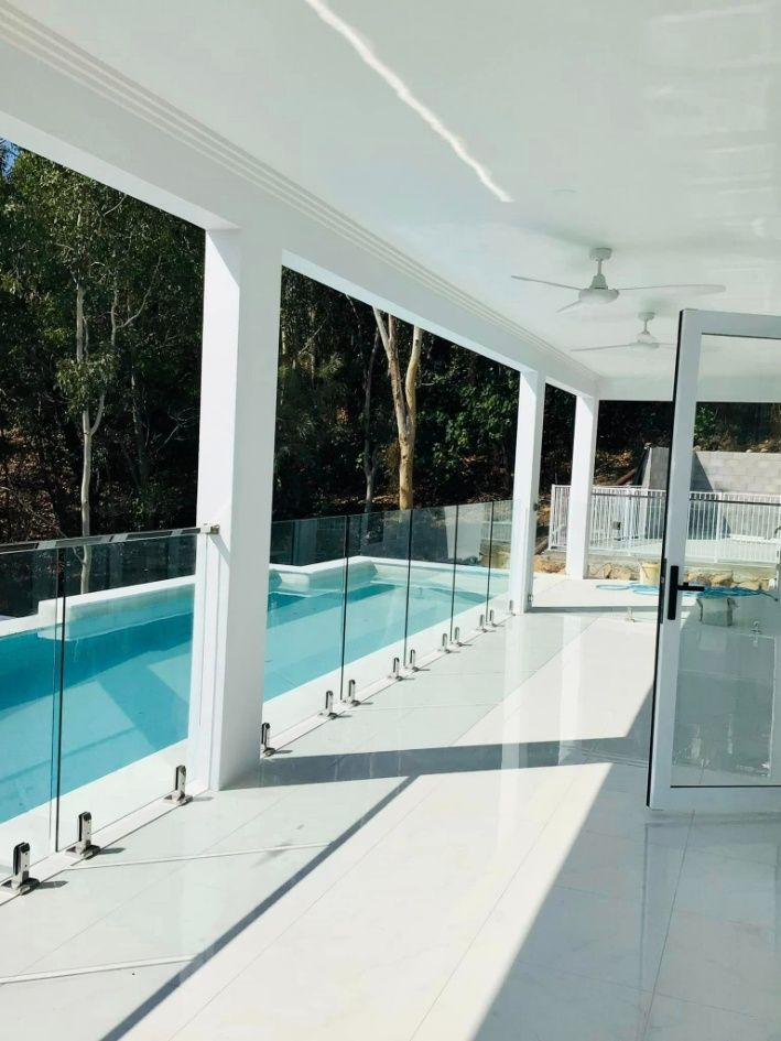 A large swimming pool is behind a glass fence — Ward's Aluminium in Garbutt, QLD