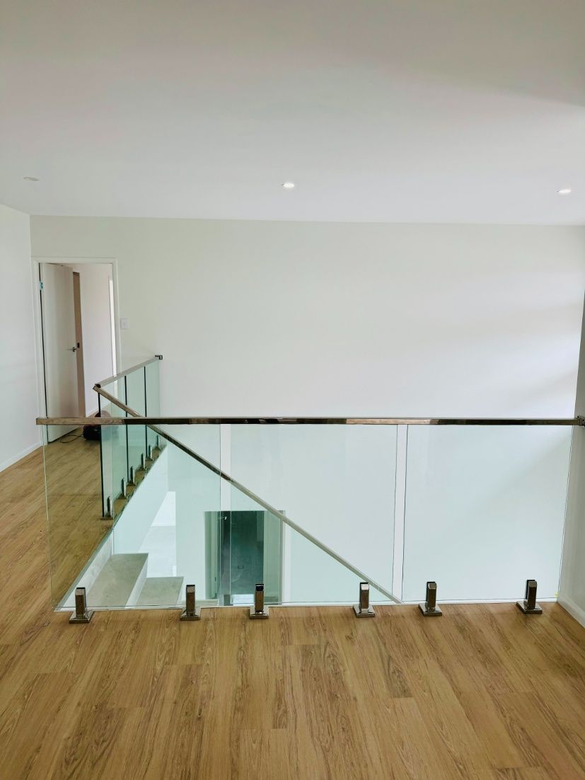 A Staircase With A Glass Railing And Wooden Floors In A House — Ward's Aluminium in Cardwell, QLD