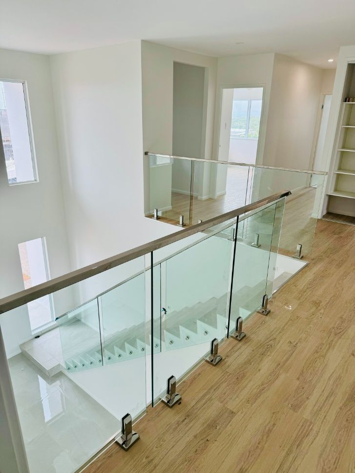 A Staircase With A Glass Railing And Wooden Floors In A House — Ward's Aluminium in Cardwell, QLD