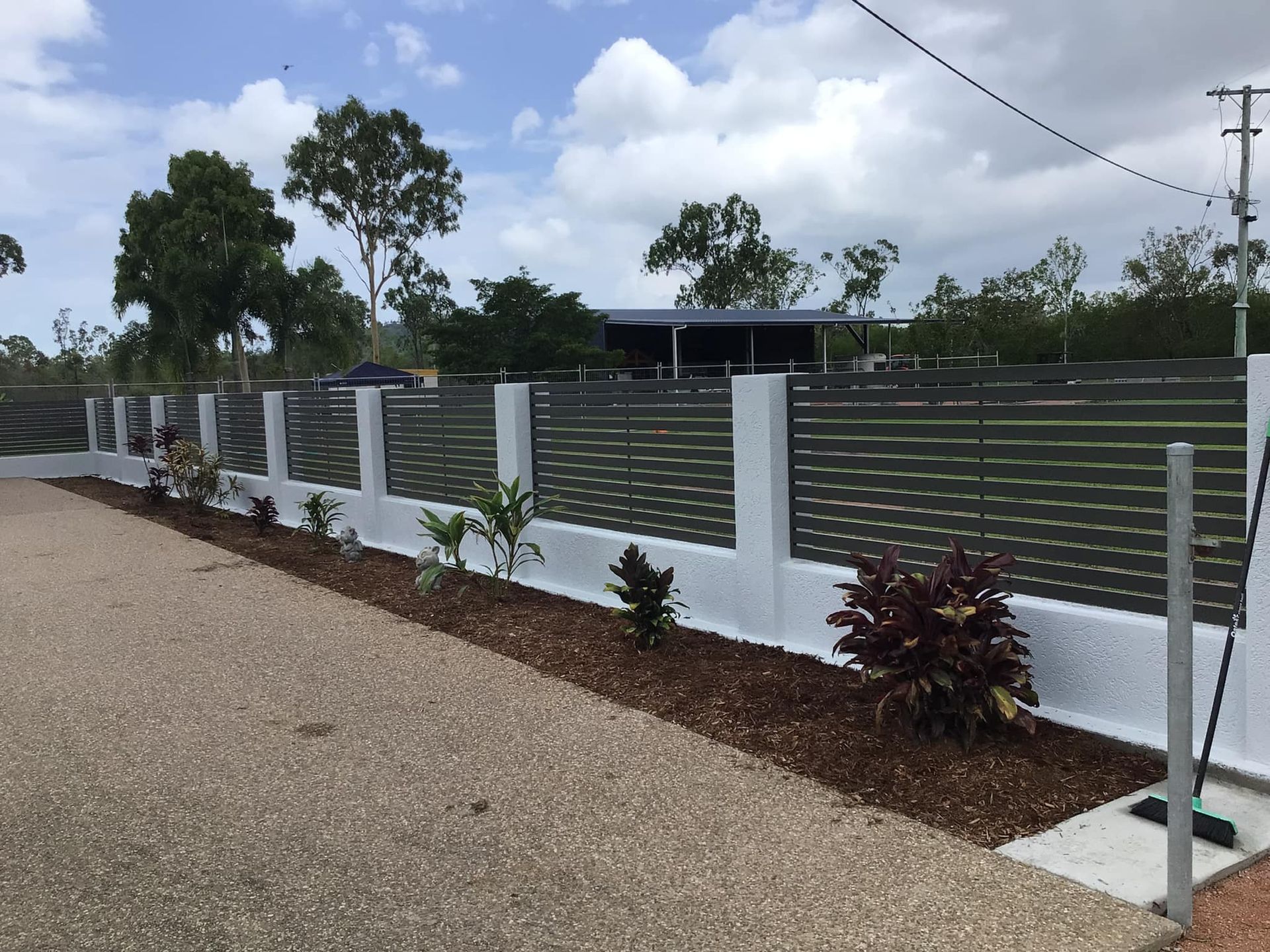 A Large green and White fence with a house in the background — Ward's Aluminium in Garbutt, QLD