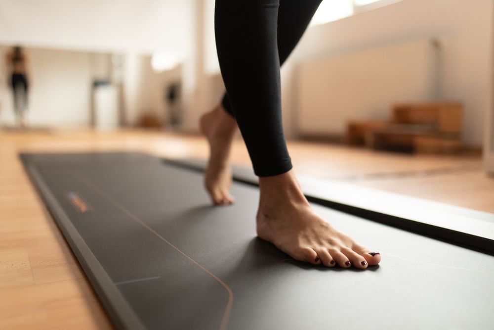 Persona che cammina a piedi nudi su un tappetino da yoga in uno studio luminoso