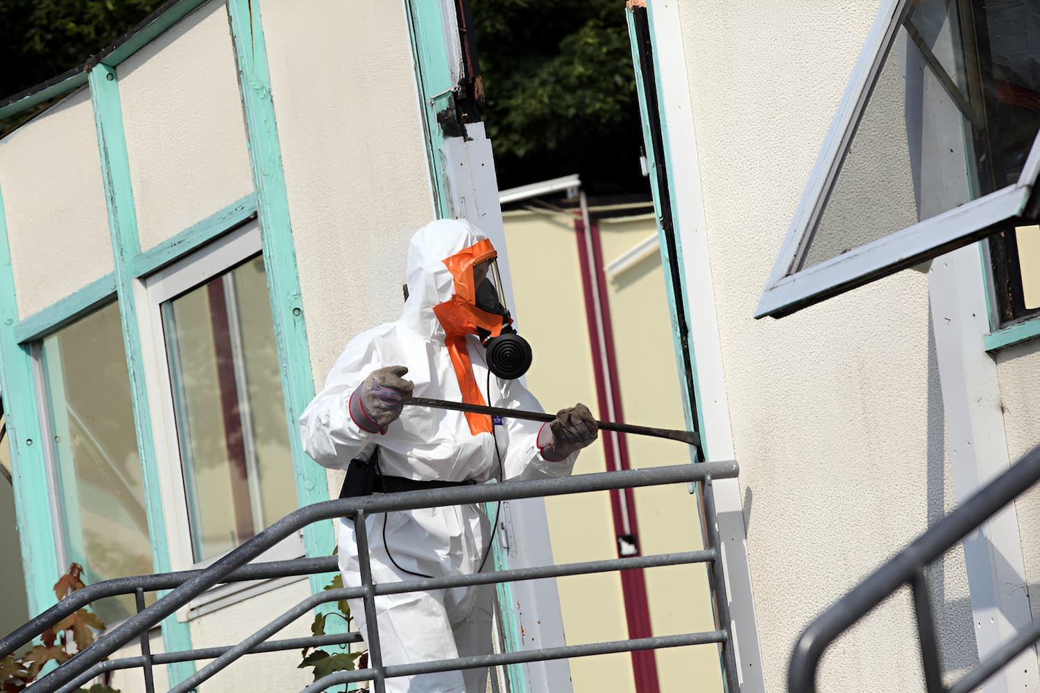 A Man Wearing a Gas Mask is Spraying a Building — Veramax Industries in Park Avenue, QLD