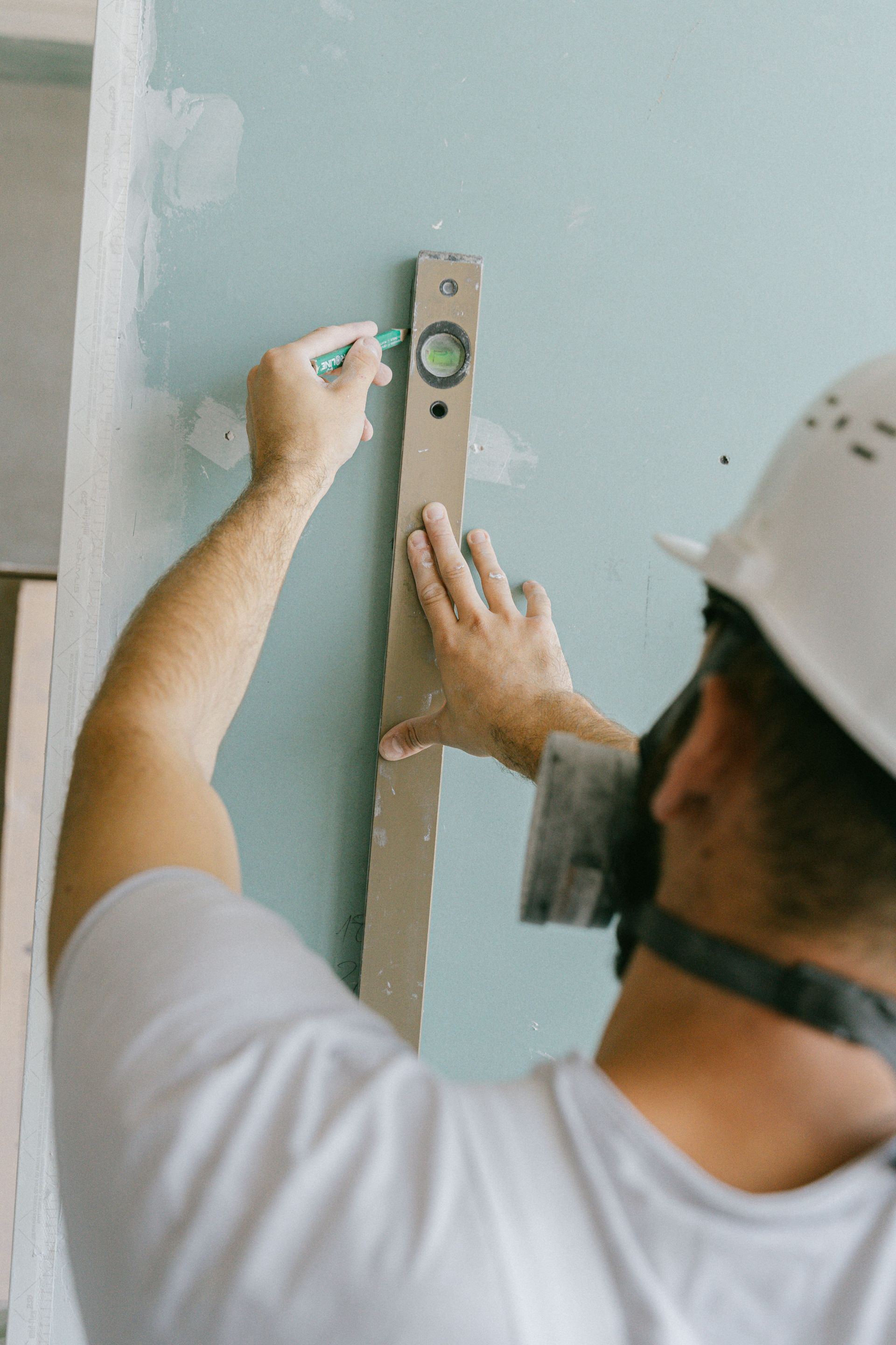Man measuring a bathroom countertop with a tape measure beside a tub and white tiled wall