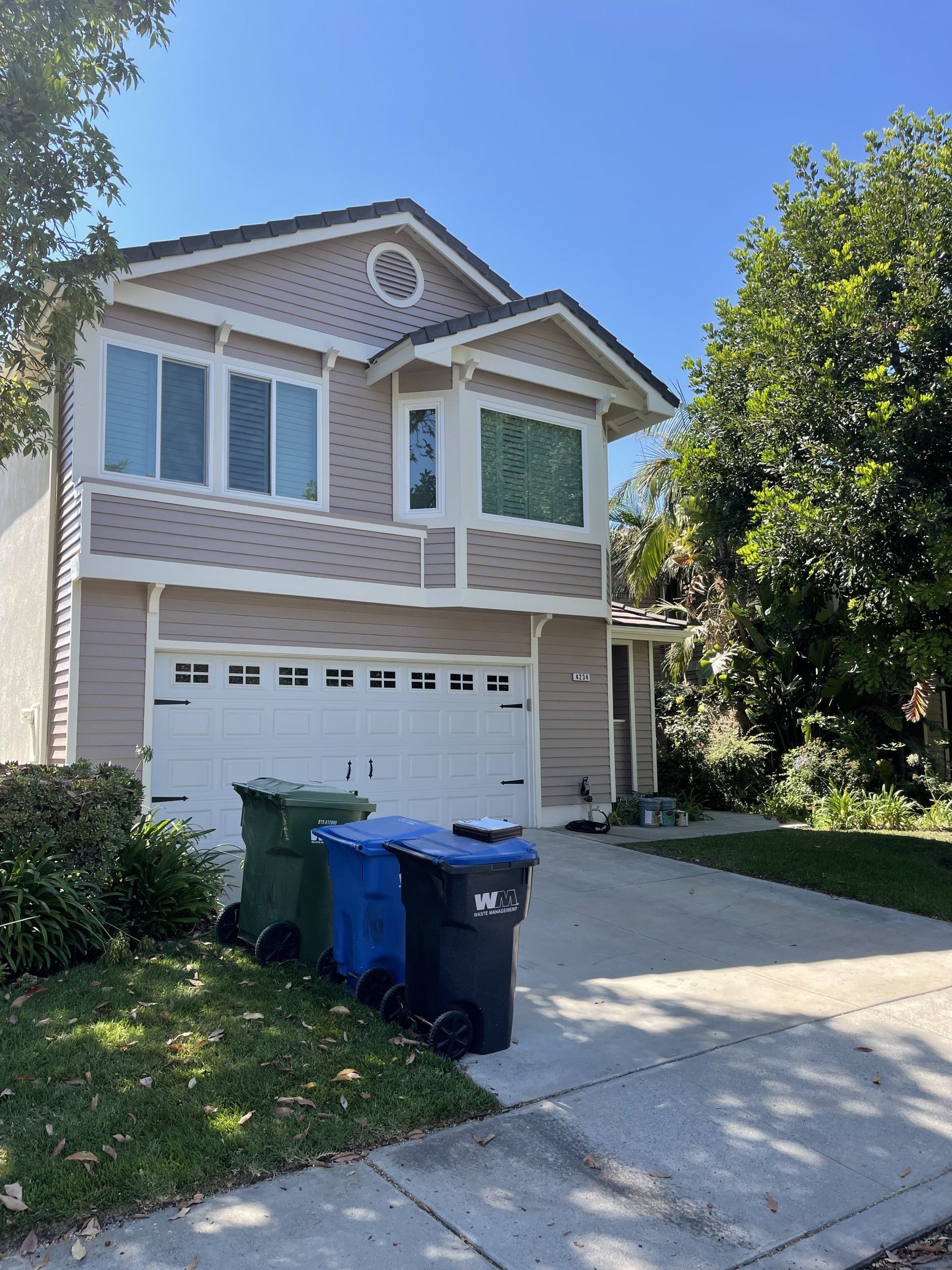 A house with three trash cans in front of it