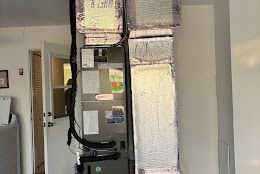 HVAC unit with insulated ductwork in a room with a doorway.