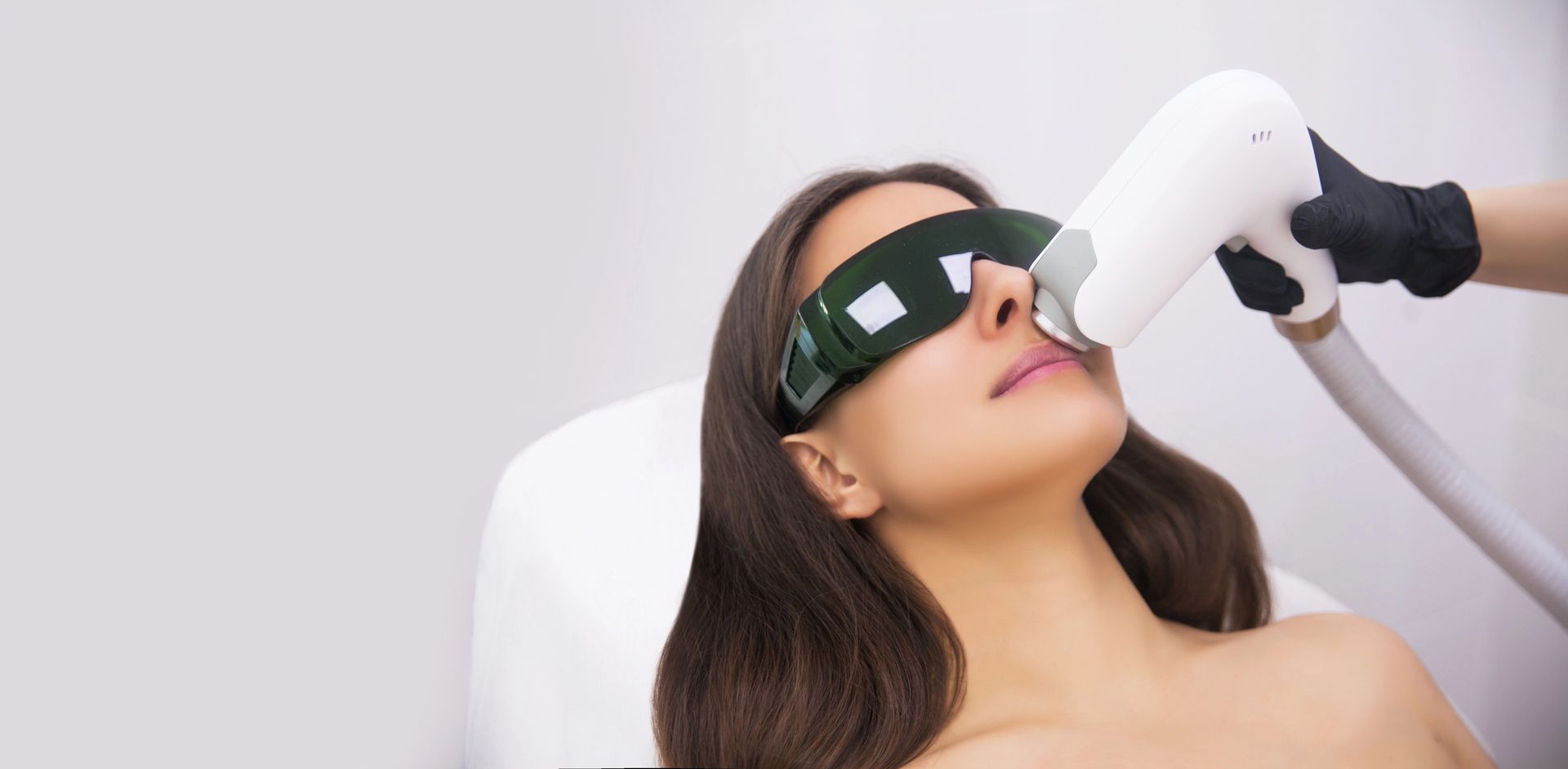 Una persona que lleva gafas protectoras recibe un tratamiento de depilación láser
