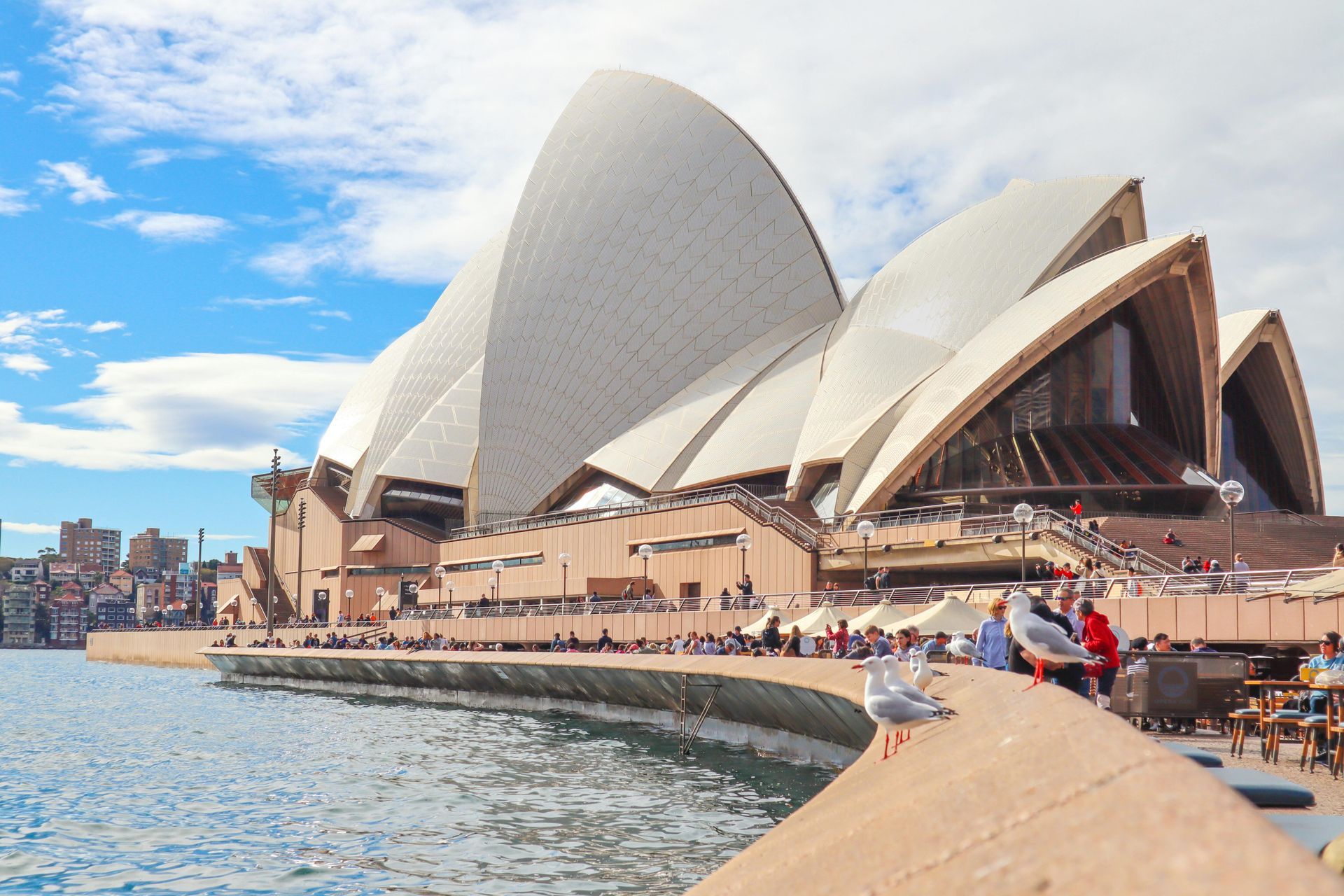 A ópera de sydney é um edifício muito grande situado no topo de um corpo d'água.