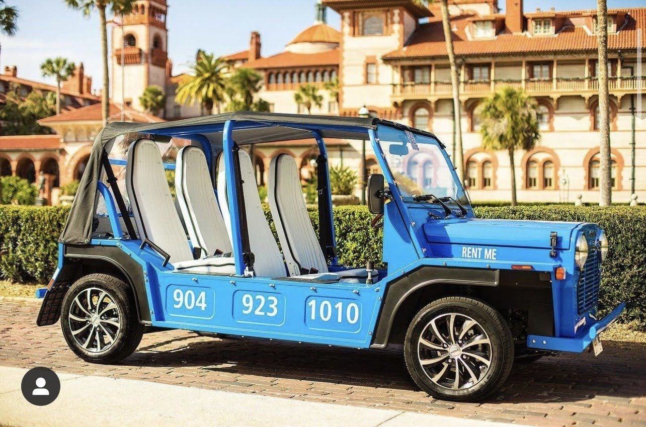 A blue jeep is parked on the side of the road in front of a building.