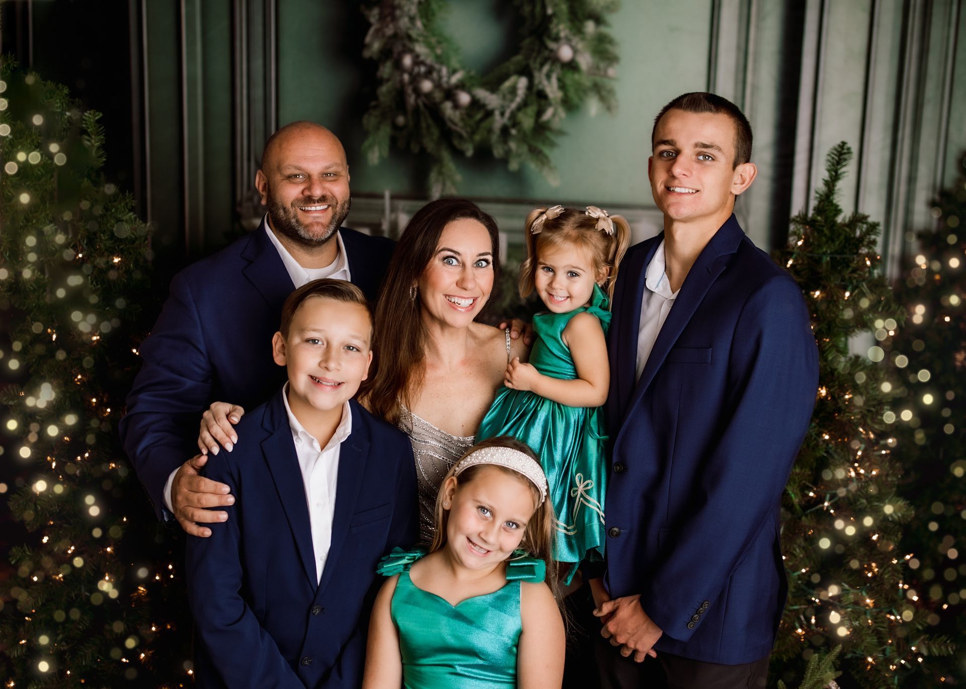 Family portrait of the Horton Family in front of Christmas trees. People are smiling.