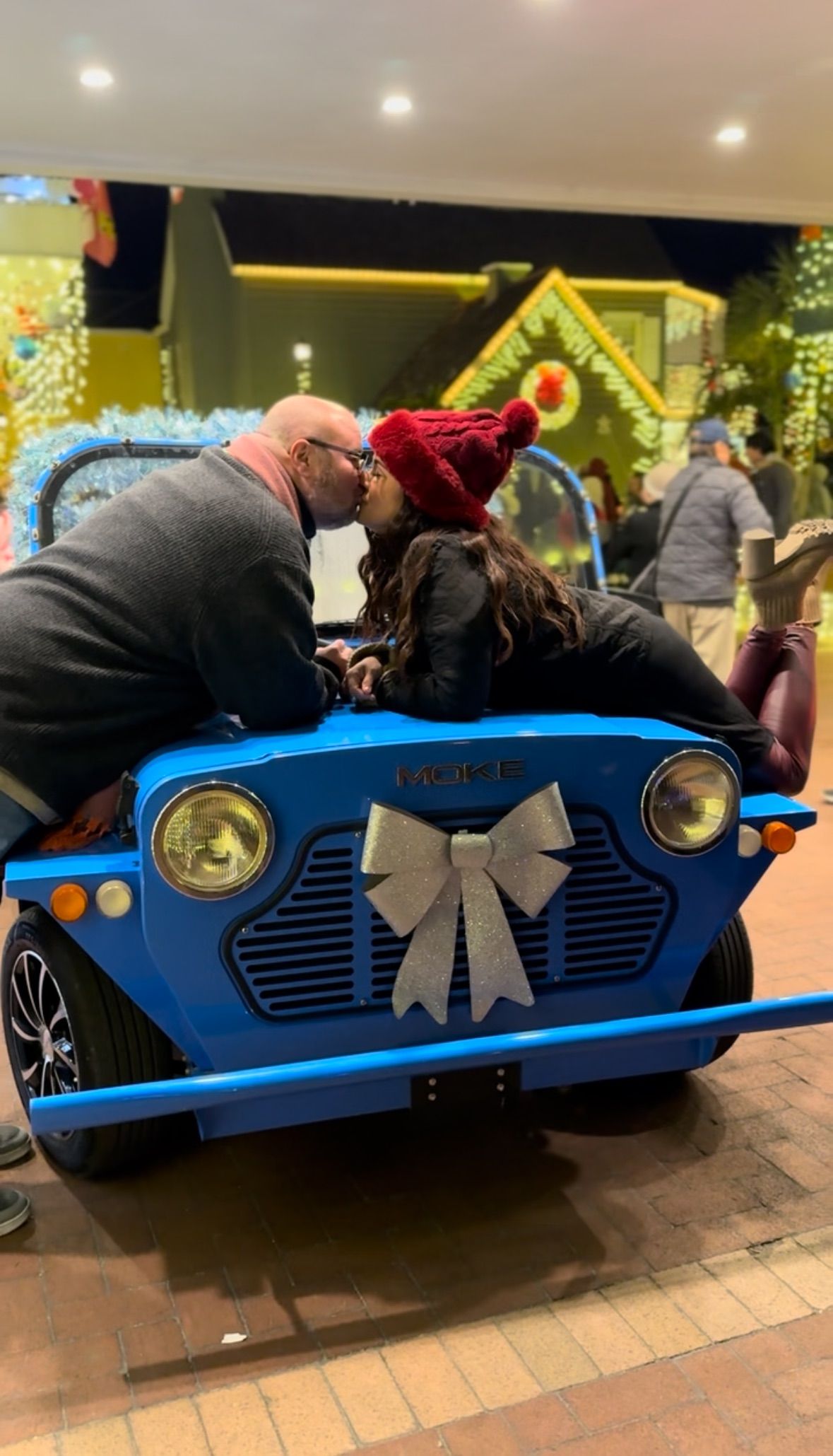 Couple kissing over a blue Moke golf cart decorated with a bow, at the Hilton Bayfront for St. Augustine Nights of Lights 