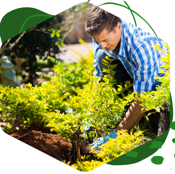 A man in a blue and white plaid shirt is working in a garden.
