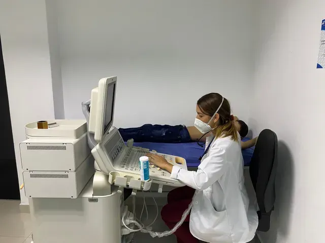 Médico utilizando un dispositivo de imágenes médicas en un paciente acostado en una camilla de exploración.