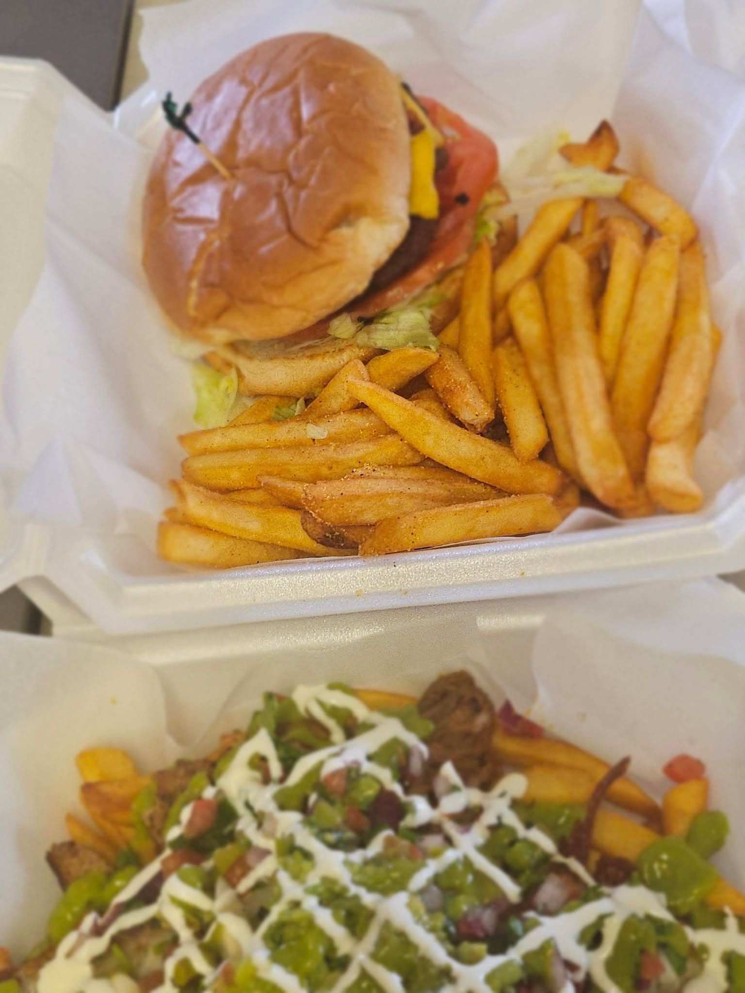 Fast-food tray with a cheeseburger, fries, and a loaded salad drizzled with white dressing