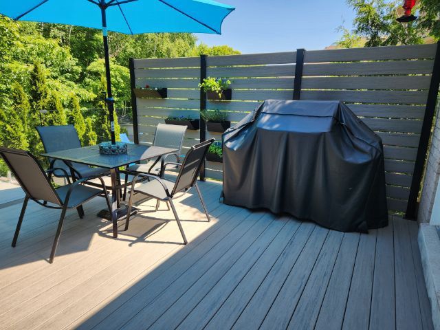 Two tone Grey Composite deck, BBQ privacy wall, glass railings, bistro set