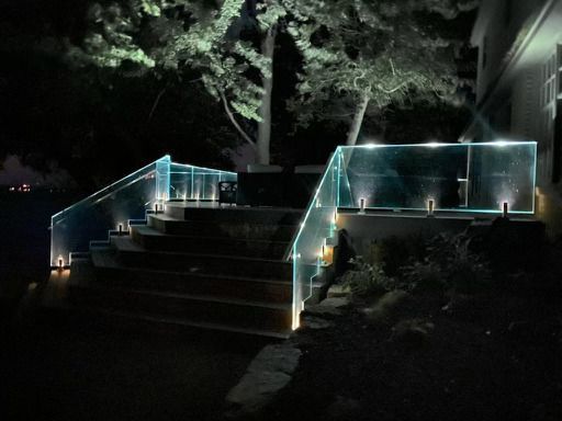 Lit glass railing on outdoor stairs at night.