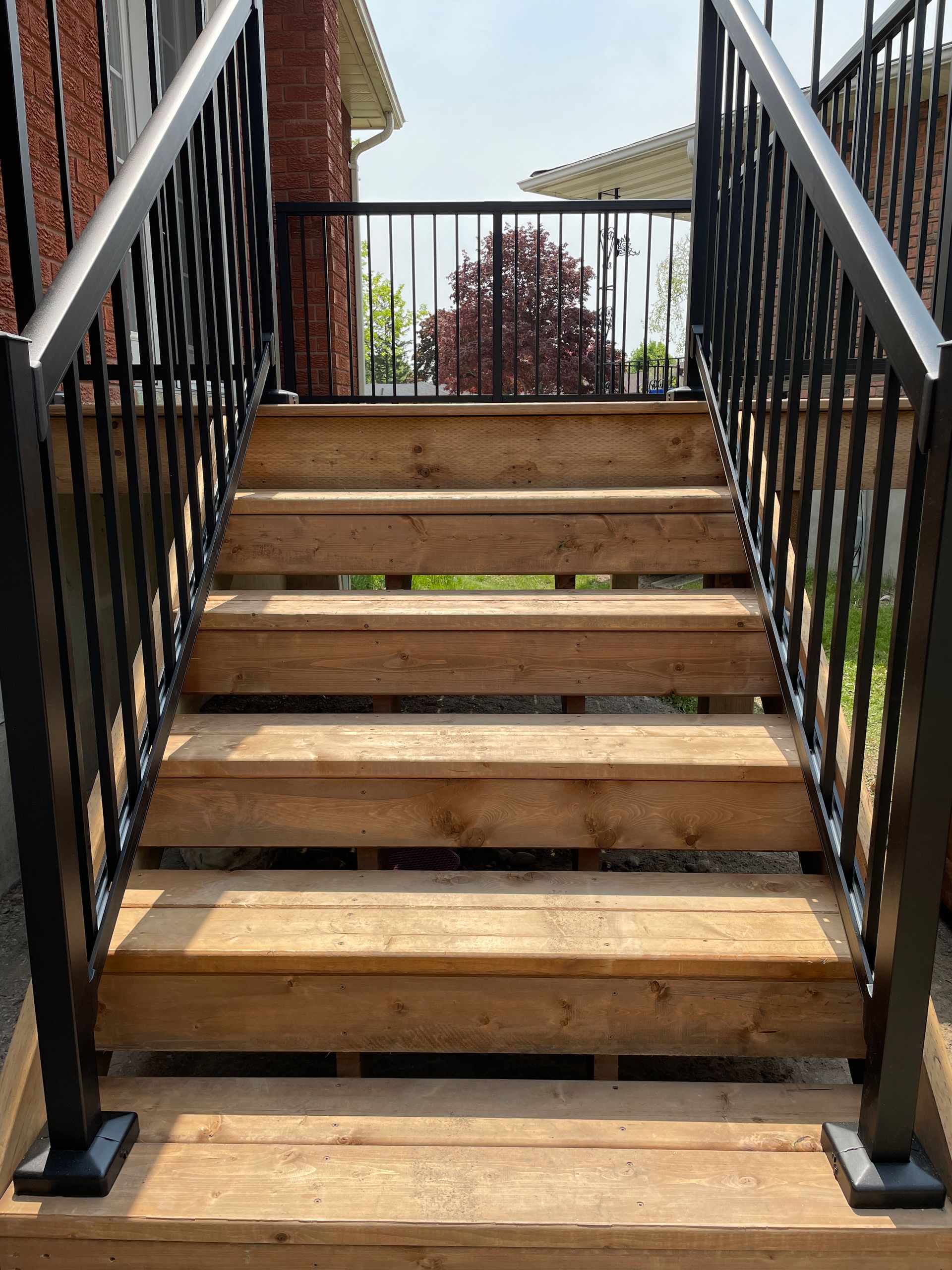 Wooden outdoor staircase with black metal railings.
