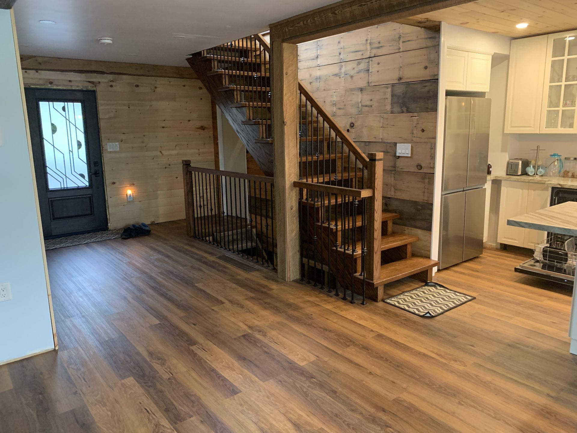 Wooden staircase in a rustic home with wooden floors, leading upstairs, next to a kitchen.
