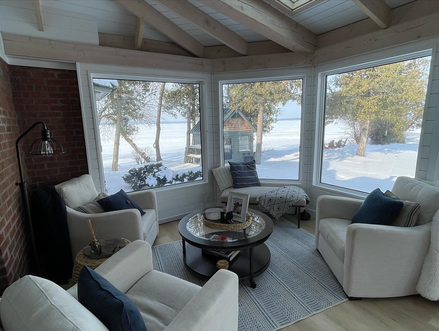 Sunroom with white armchairs, round table, and a snowy outdoor view.
