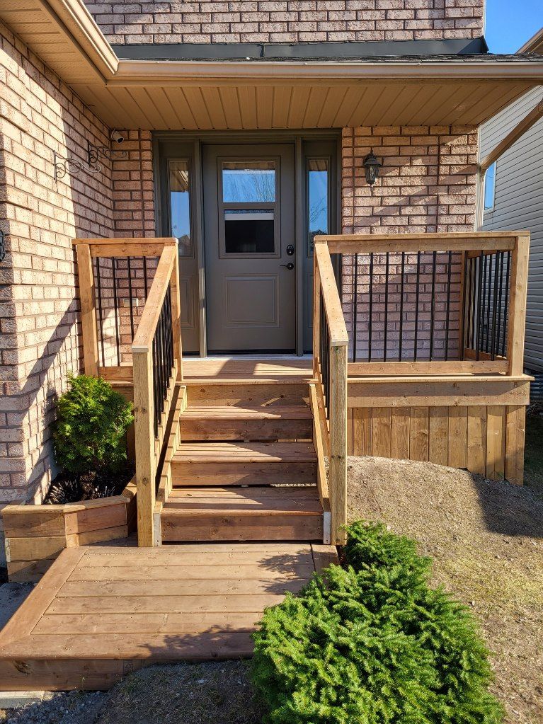 Brick house entrance with wooden stairs, railing, and a door.