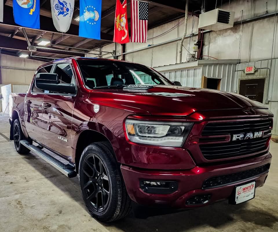 Red RAM pickup truck parked inside a garage, with black wheels and a RAM logo.