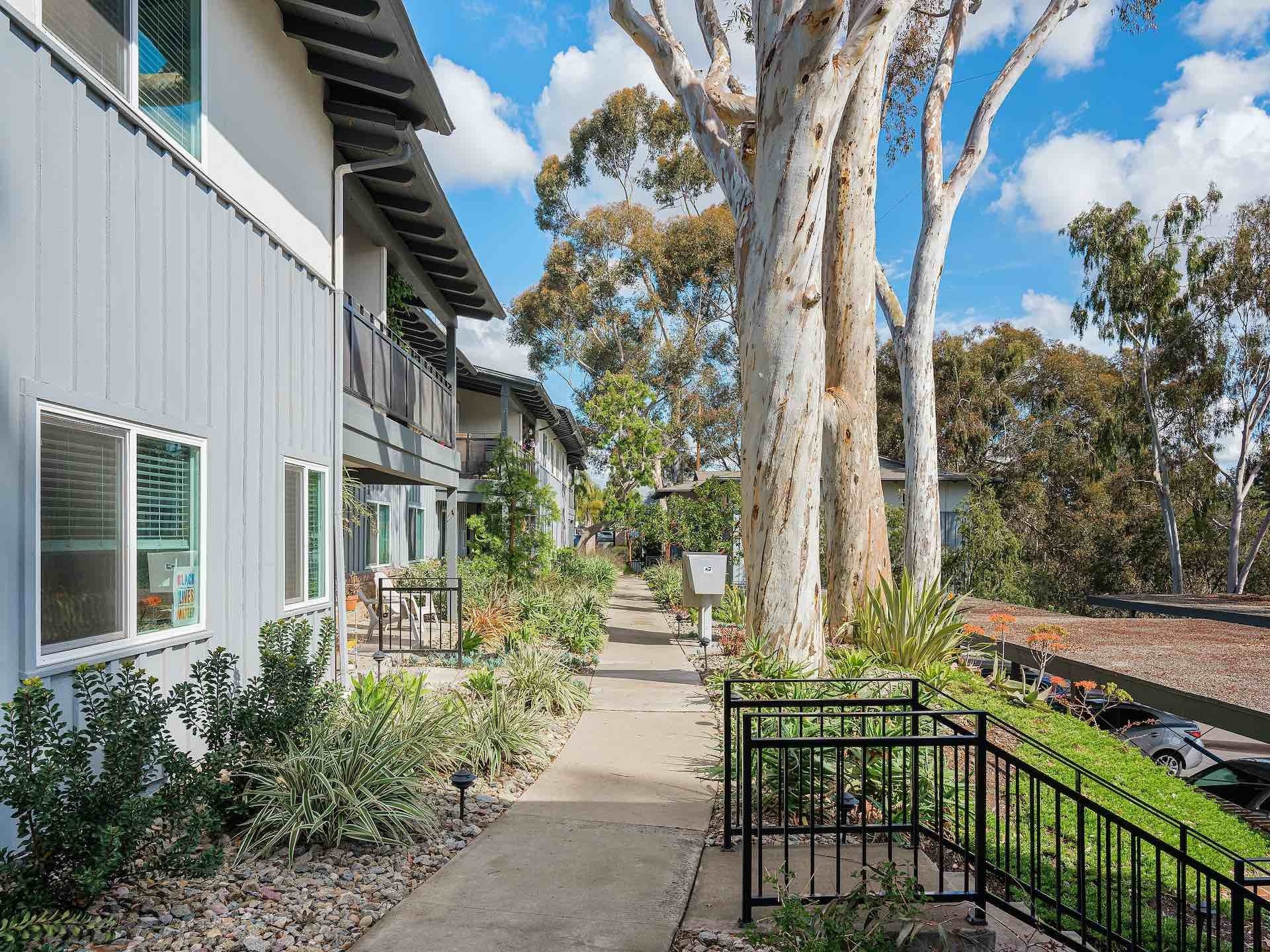 Exterior walkway of apartment complex with trees covering walkway