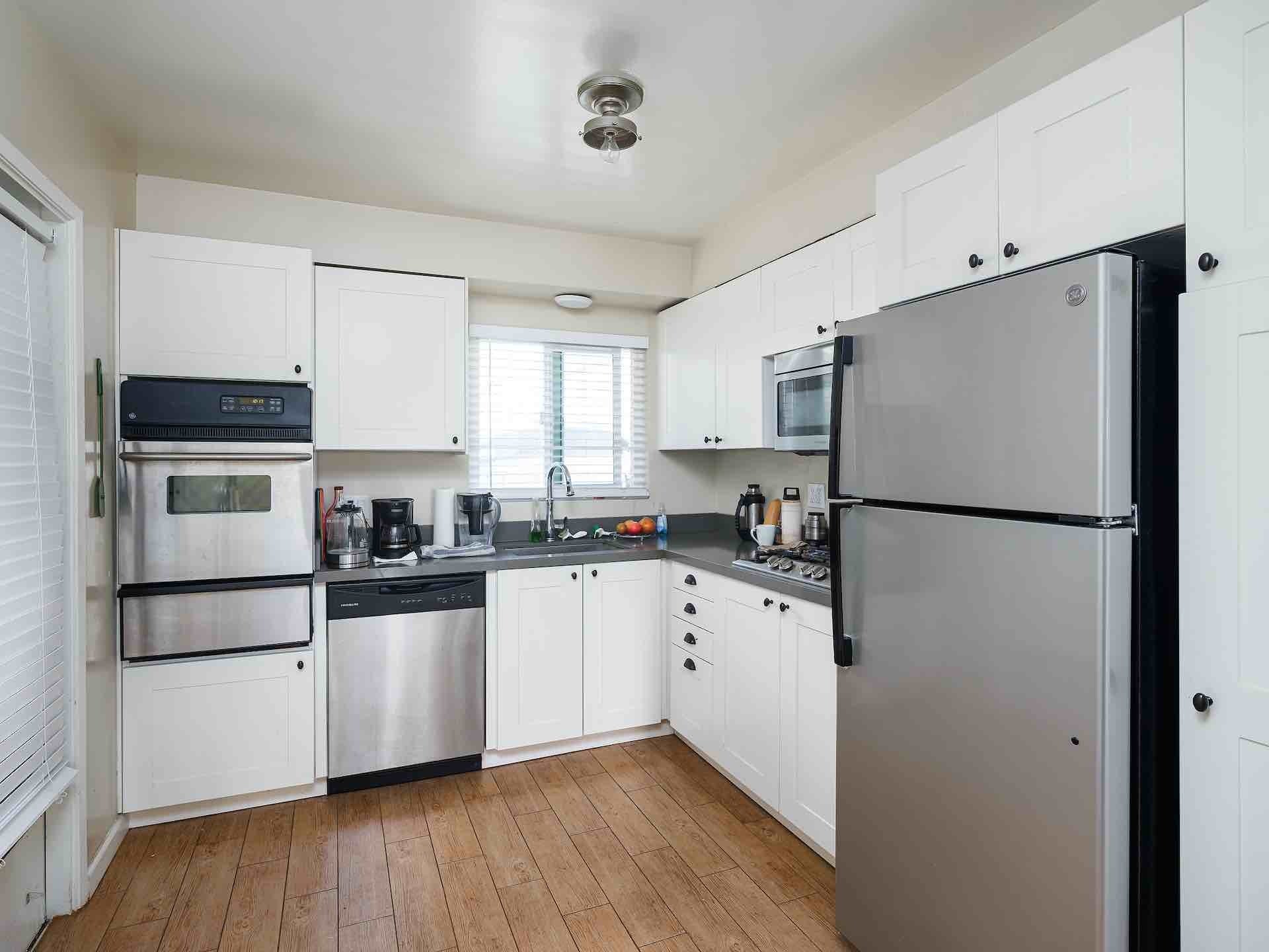 Interior of kitchen with white cabinetry and stainless steel appliances