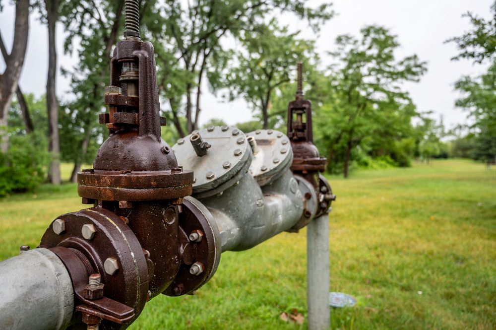 A Close Up of a Rusty Pipe in a Field With Trees in the Background — Treatwater & Plumbing Pty Ltd in North Mackay, QLD