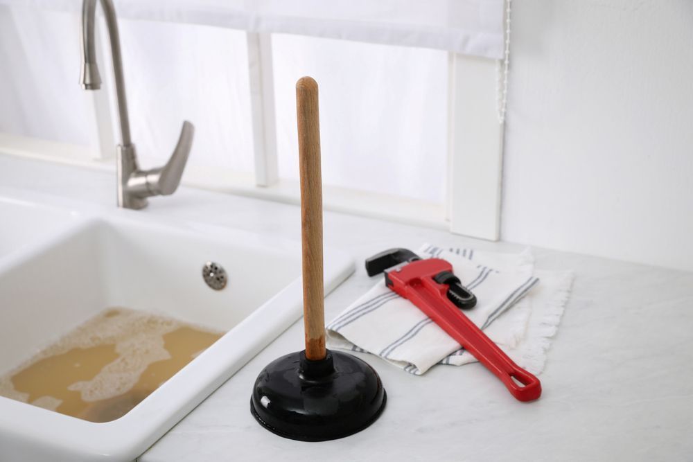 A Sink With a Plunger and a Wrench on the Counter — Treatwater & Plumbing Pty Ltd in North Mackay, QLD