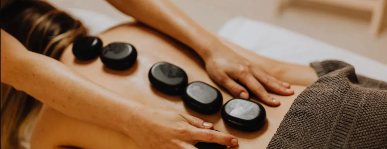 A woman is getting a hot stone massage as part of a bull body massage.