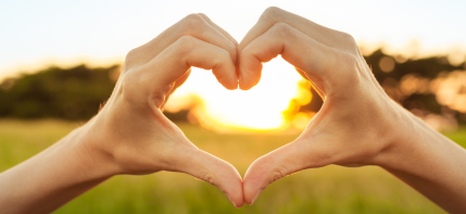 A person is making a heart shape with their hands.