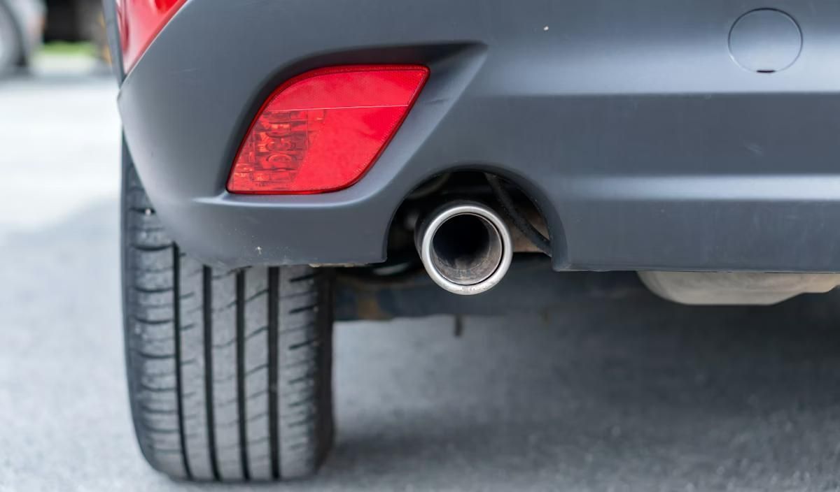 Rear View of A Gray Car, Showing a Tire and Chrome Exhaust Pipe on A Snowy Road — Brian Turner Automotive in Stuart Park, NT
