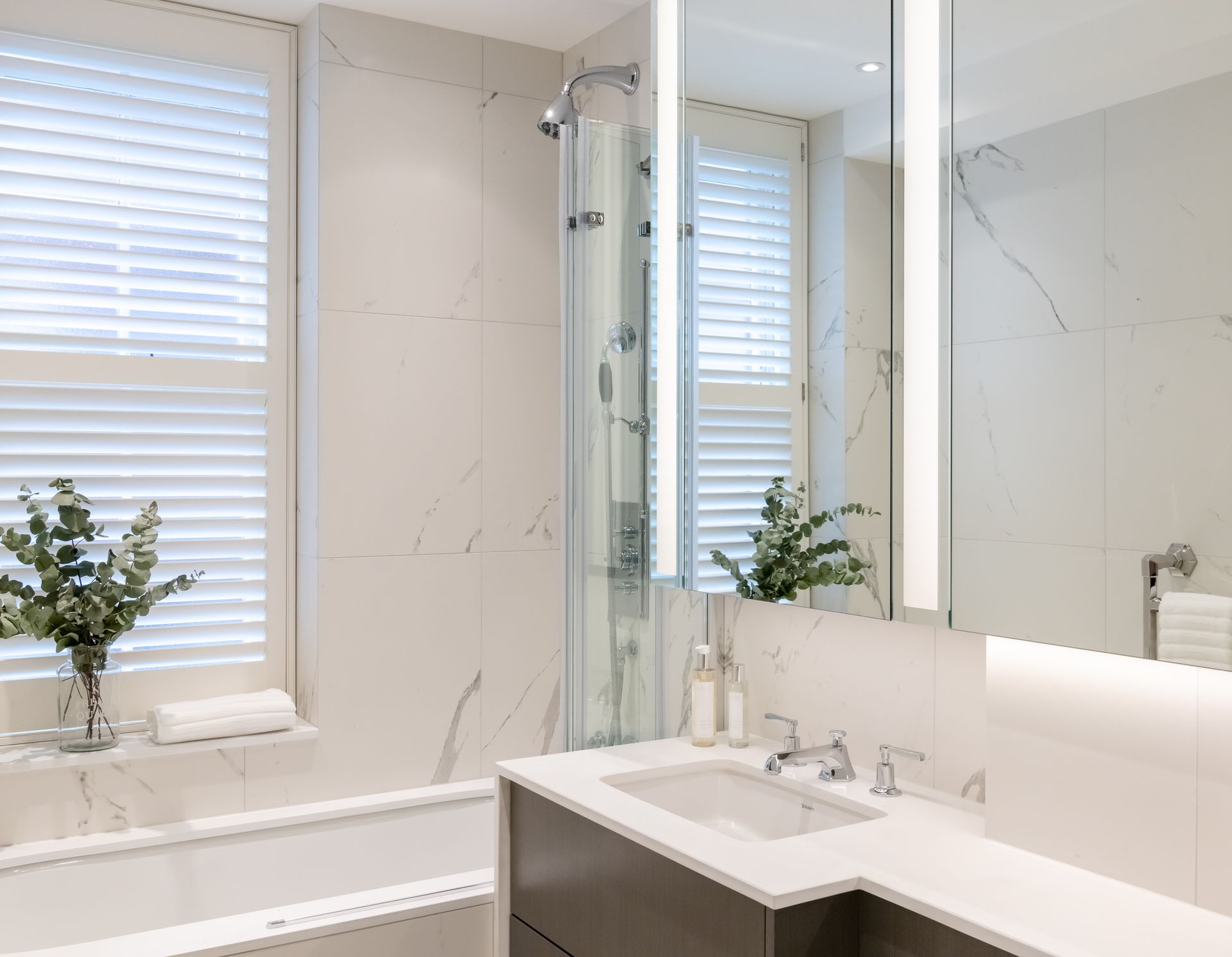 a bathroom with a sink , tub , shower and mirror 