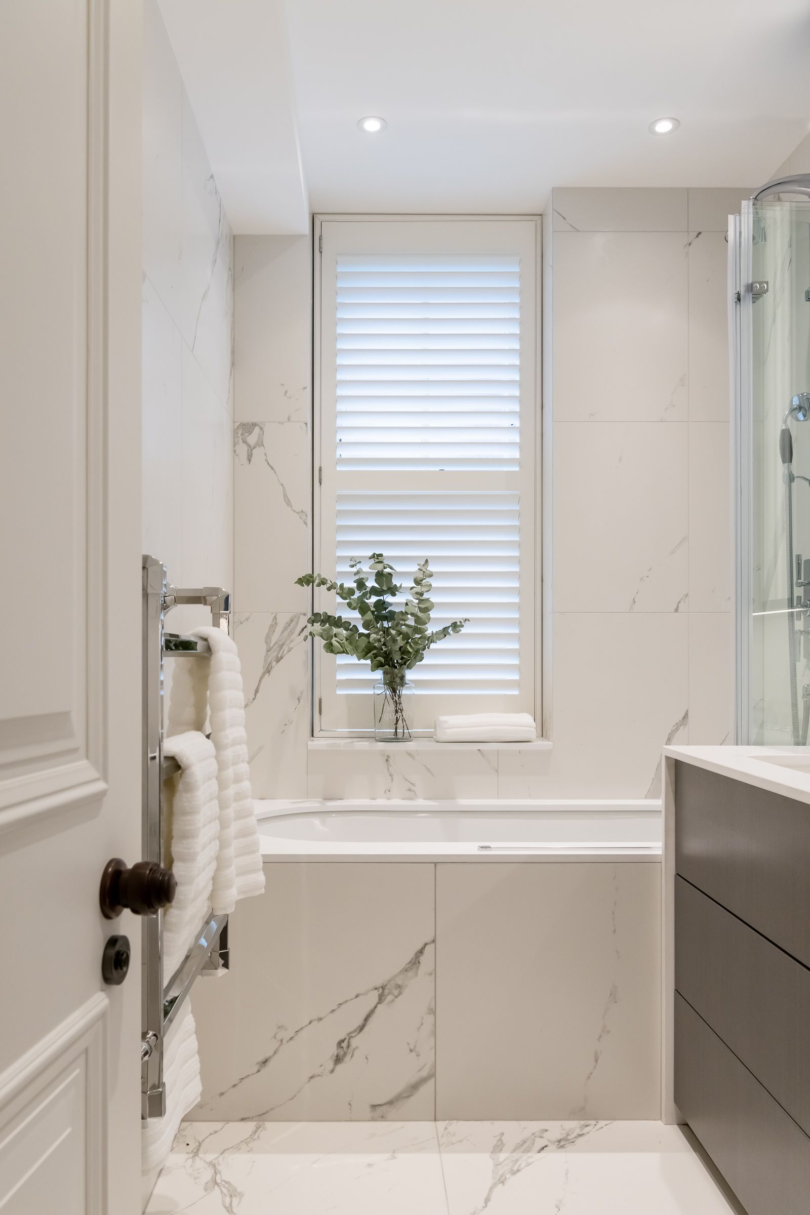 a bathroom with a tub , sink , window and towel rack 