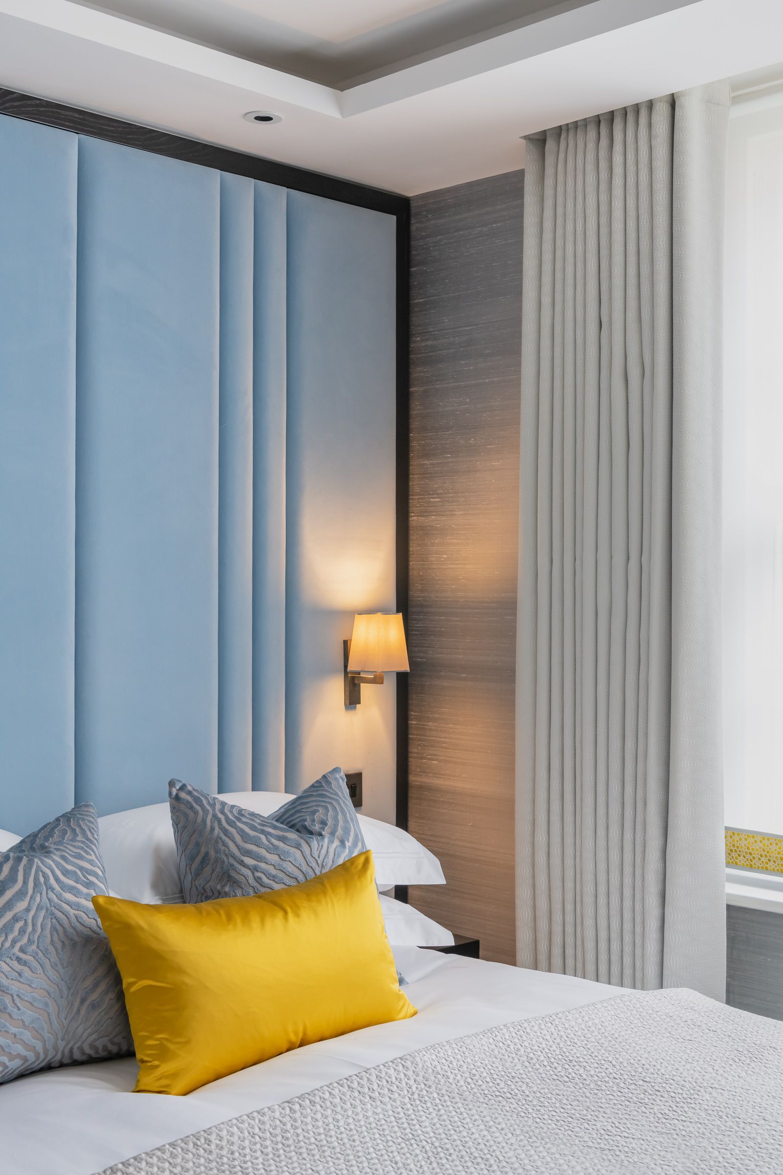 a bed with a blue headboard and yellow pillows in a hotel room 
