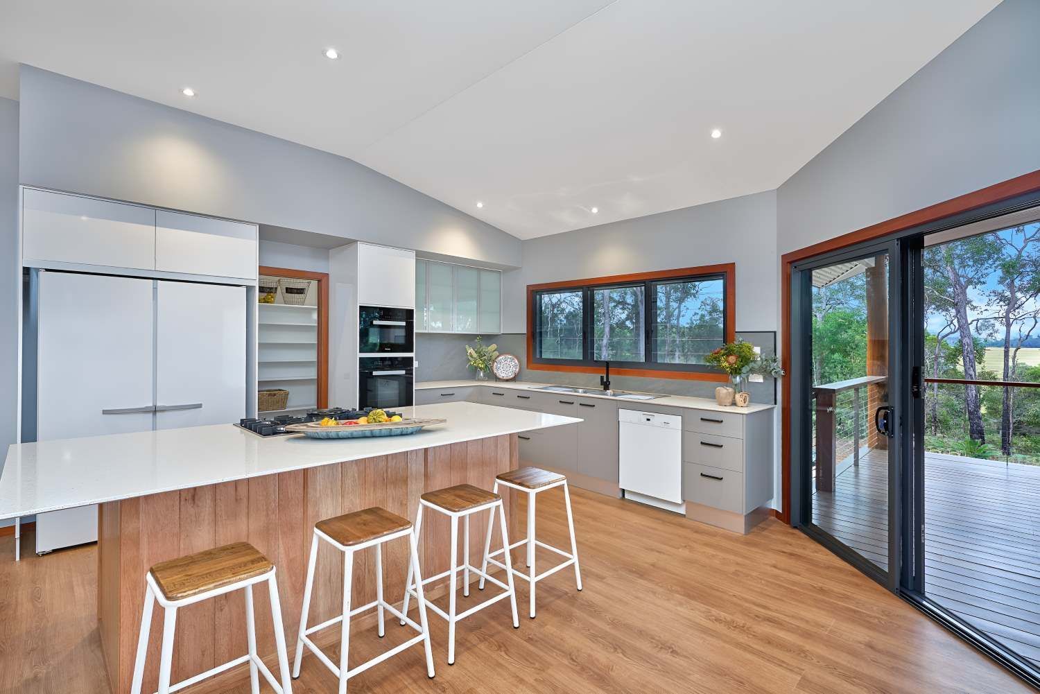 A Kitchen With a Large Island and Stools and a Large Window — ROGA Build Solutions in Atherton, QLD