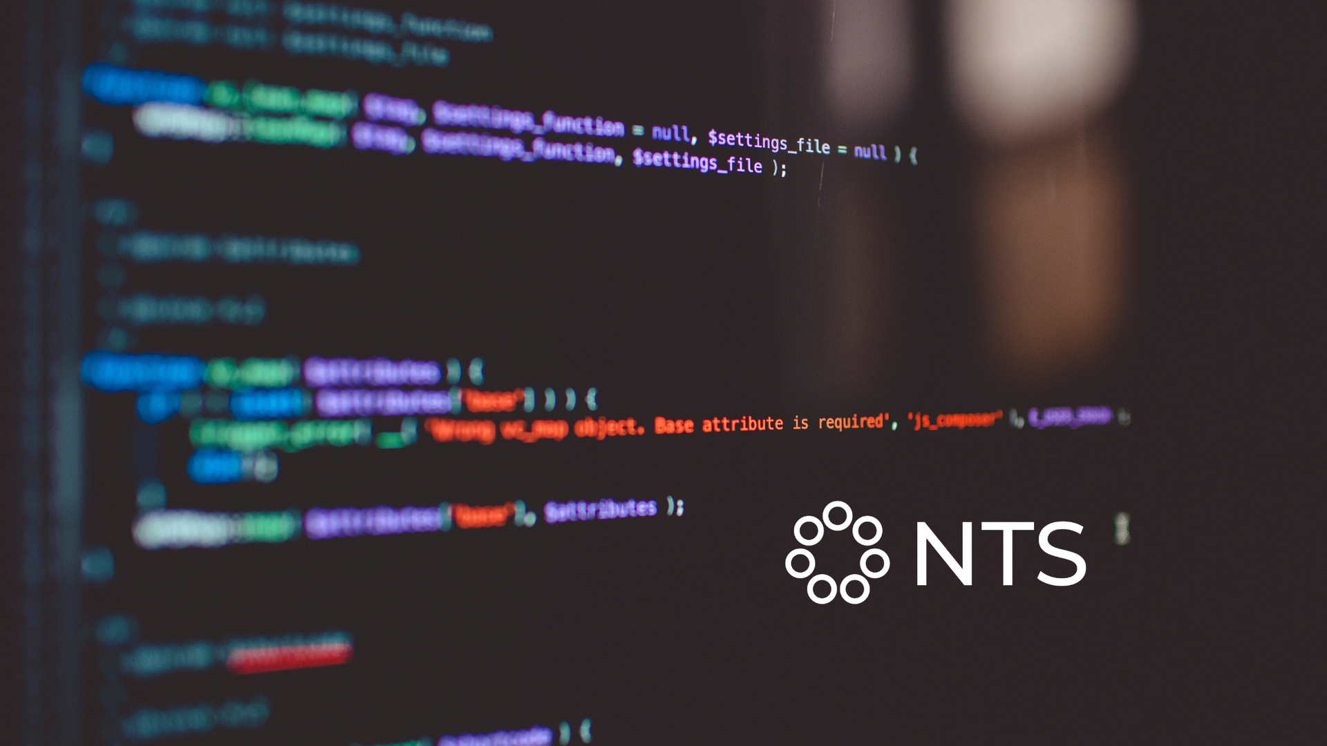 Blurred code editor with colorful syntax highlighting and NTS logo on the right