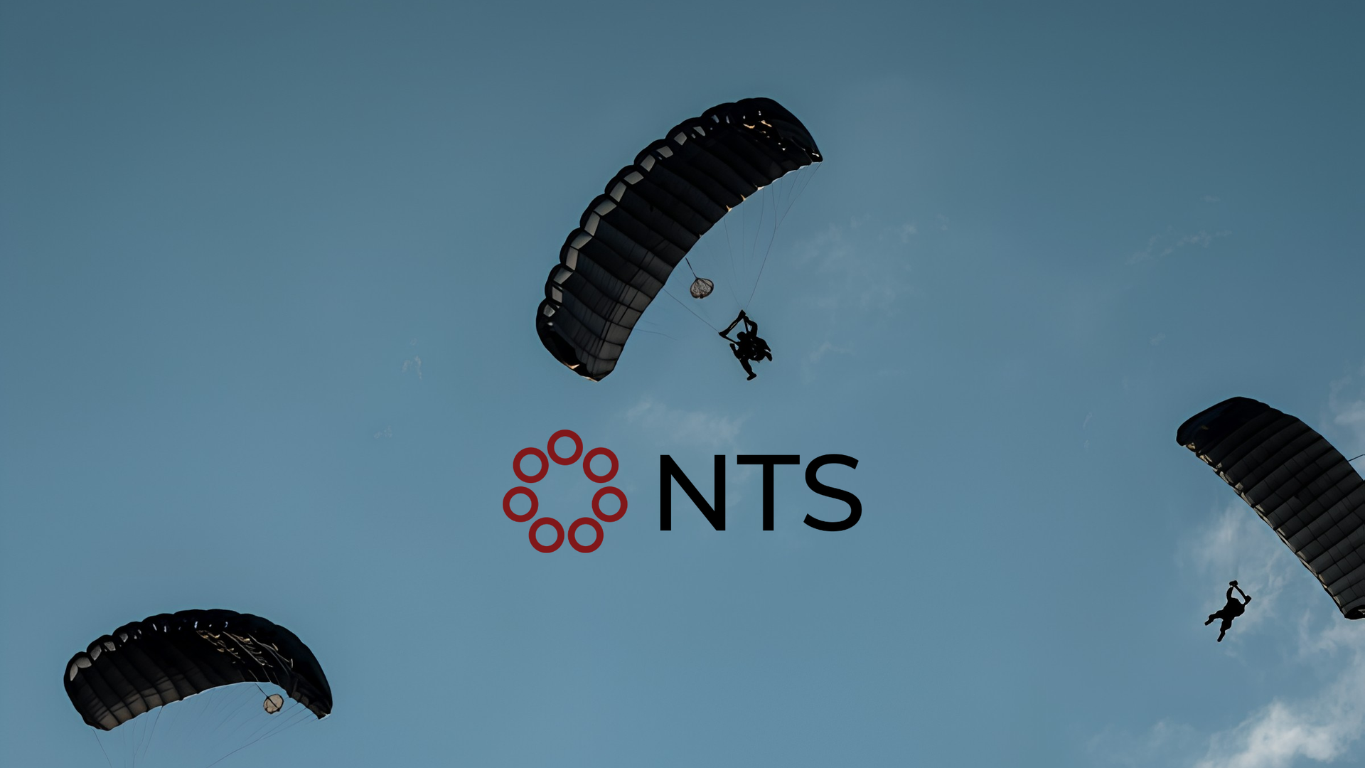 Three skydivers under black parachutes above an NTS logo on a blue sky background