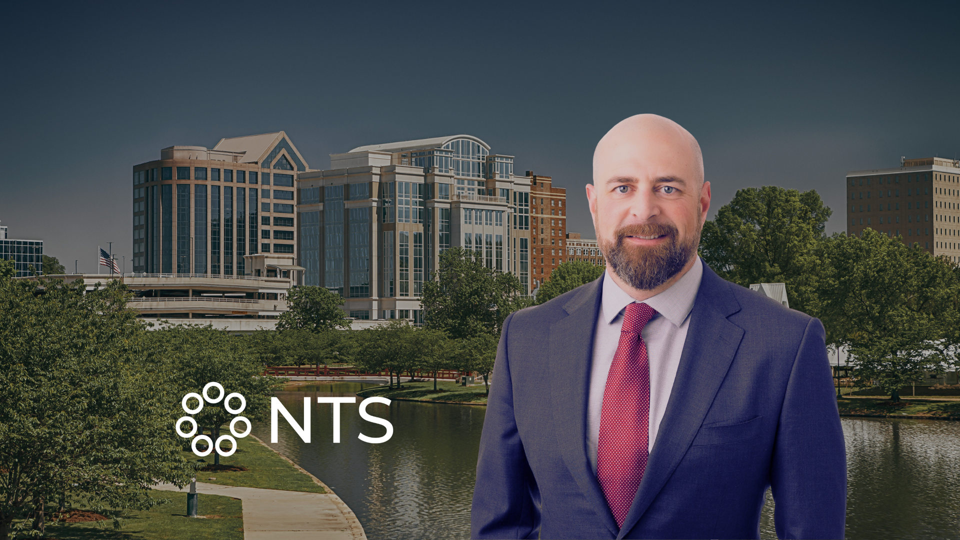 NTS logo beside a man in a navy suit and red tie, standing before a modern office building.
