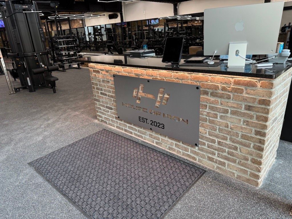 Brick-front bar counter with a metal sign in an indoor gym or lounge setting
